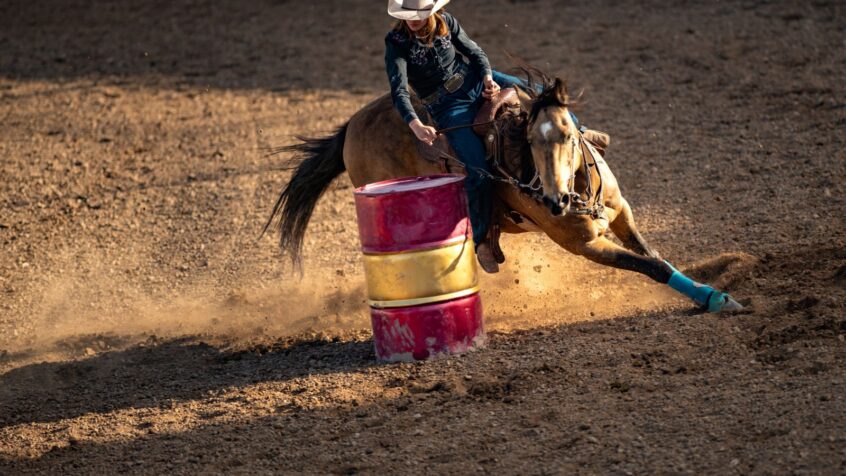 woman sitting in a barrel racing saddle turns around a barrel